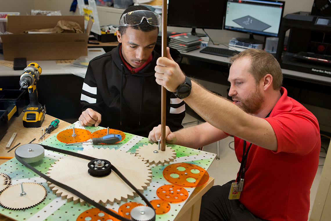 Teacher assisting student with engineering project