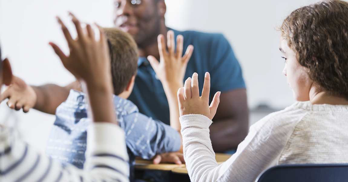 students holding up hands in class