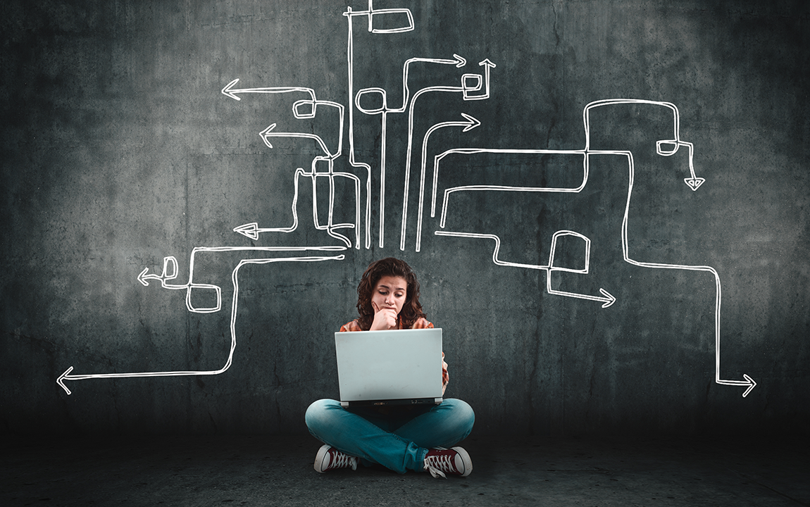 student on a computer in front of a chalk board: critical thinking.