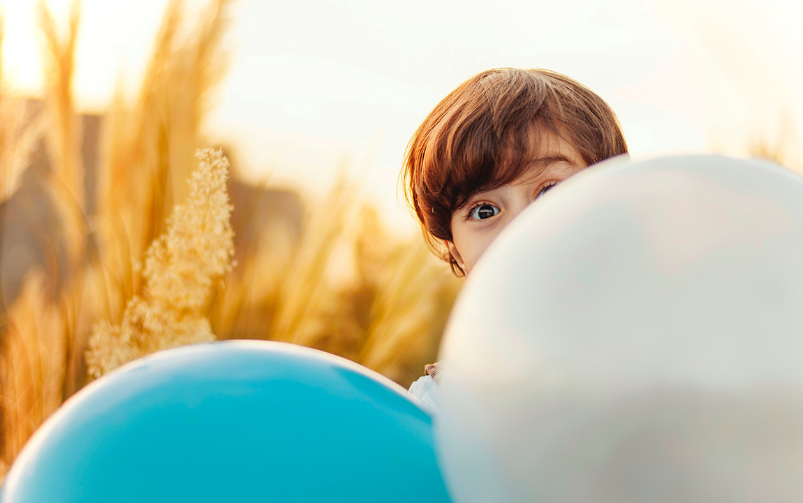 boy hiding behind balloons