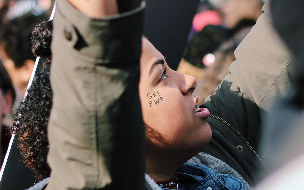 girl with arms raised and girl power sticker on cheek