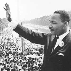 Martin Luther King, Jr. at the National Mall in Washington DC. His hand is raised waving at the crowd.