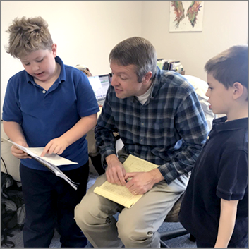 two young student presenting to a senior aged man