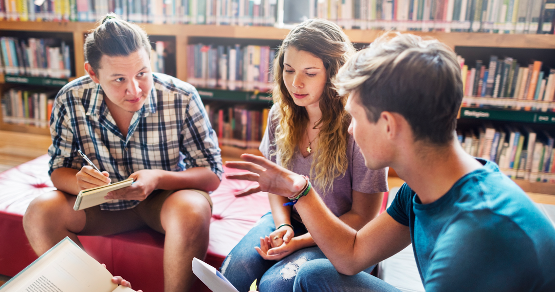 three students talking in library