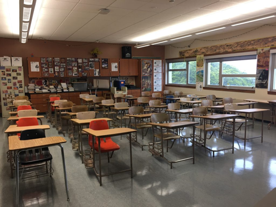 A view of a classroom. All the desk in long rows, one in front of the other.