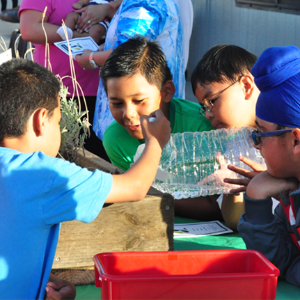 student watering a garden in a PBL outdoor classroom session