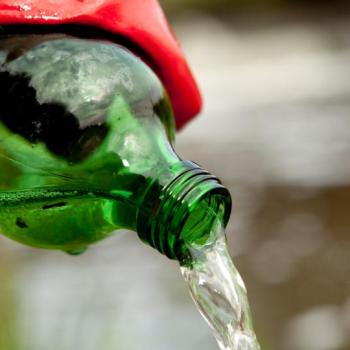 Person pouring water out of a bottle wearing a rubber glove