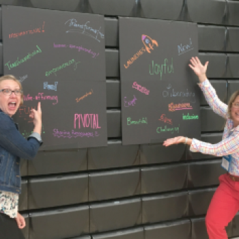 two teachers point at two board with single word descriptions of high-quality PBL