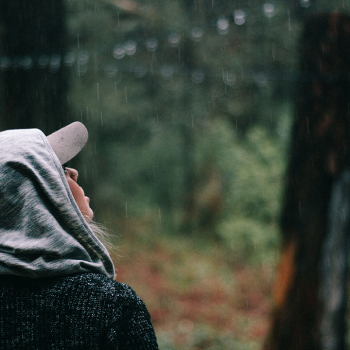 woman looking at the rain in the forest