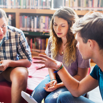 three students talking in library