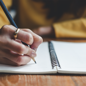 teacher writing reflection in notebook