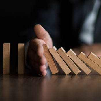 a hand breaking a chain of dominoes falling