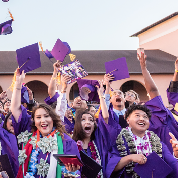 group of students in graduation gowns, throwing their caps