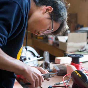 Boy working on boat project with pliers 