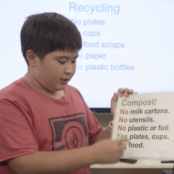 Young male student presenting card in class