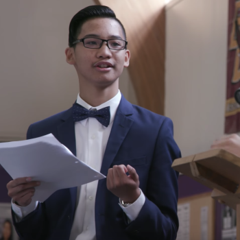 Student dressed in formal wear presenting a paper