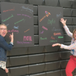two teachers point at two board with single word descriptions of high-quality PBL