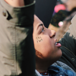 girl with arms raised and girl power sticker on cheek