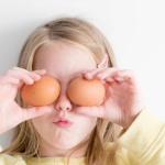 girl holding eggs to her face like eyes