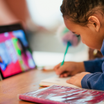 young student working with pencil, notebook, and ipad at kitchen table